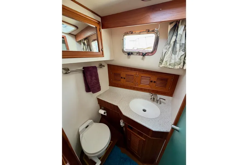 Slide: The Image of 1988 Offshore Yachts 48 Sedan bathroom with sink, toilet, and wooden cabinetry. - 70
