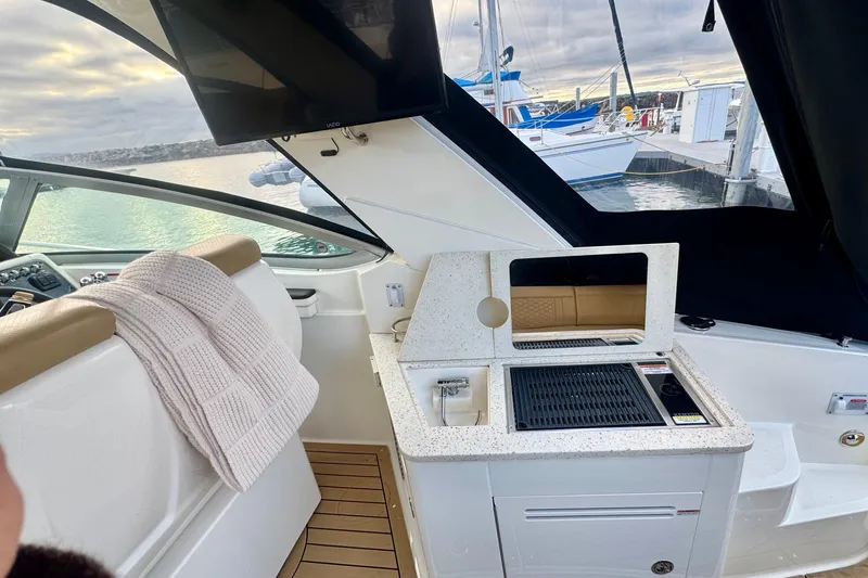 Slide: The Image of 2021 Sea Ray Sundancer 350 yacht interior with kitchenette and scenic marina view. - 15