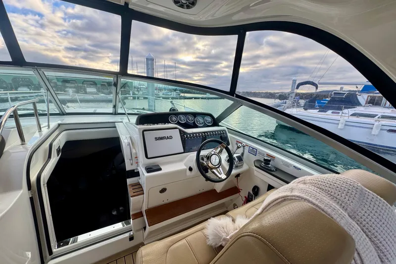 Slide: The Image of 2021 Sea Ray Sundancer 350 helm with modern controls, docked at marina under cloudy sky. - 23