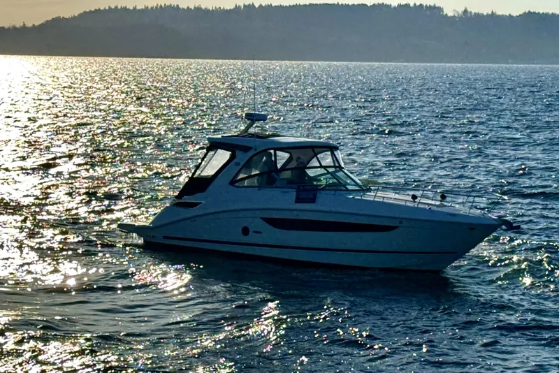 Slide: The Image of 2021 Sea Ray Sundancer 350 yacht cruising on shimmering water at sunset. - 26