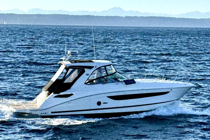 Slide: The Image of 2021 Sea Ray Sundancer 350 cruising on open water with scenic mountain backdrop. - 27