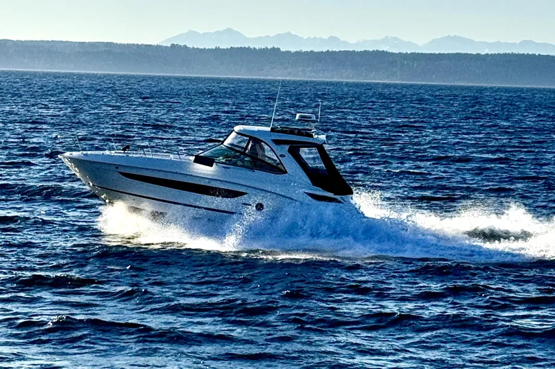 Slide: The Image of 2021 Sea Ray Sundancer 350 cruising on open water with mountains in the background. - 34