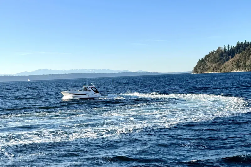Slide: The Image of 2021 Sea Ray Sundancer 350 cruising on a scenic blue ocean near a forested coastline. - 36