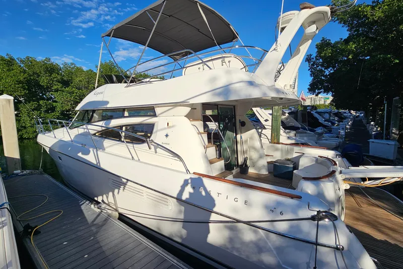 The Image of 2005 Prestige 46 yacht cruising near waterfront homes and high-rise buildings. - 0