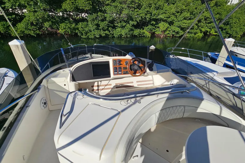 Slide: The Image of Prestige 46 yacht from 2005 docked near lush green trees. - 12