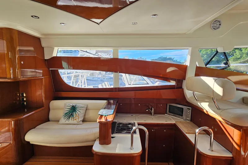 Slide: The Image of Cockpit of 2005 Prestige 46 yacht with steering wheel and control panel, docked by lush greenery. - 18