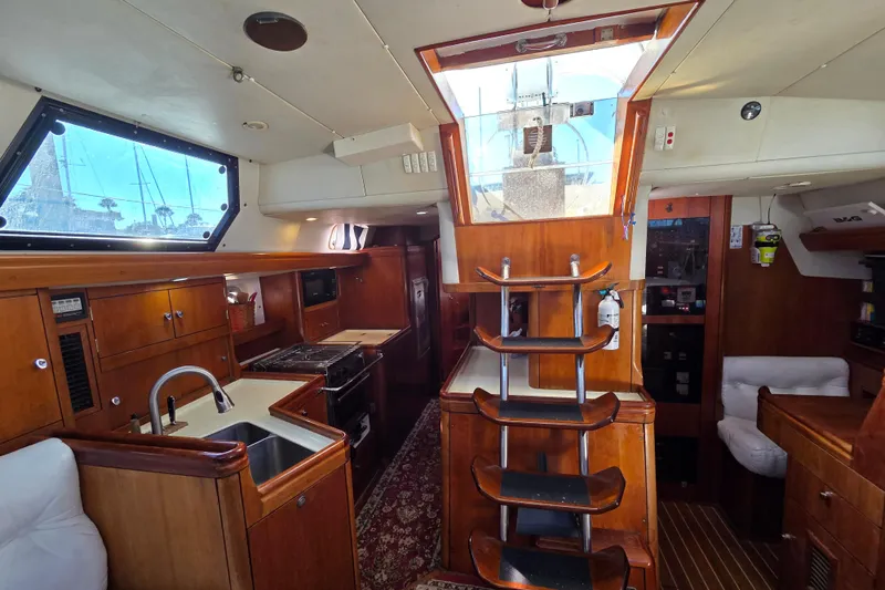 Slide: The Image of Luxurious interior of 1998 Oyster 485 Deck Saloon with white leather seating and wooden finishes. - 10