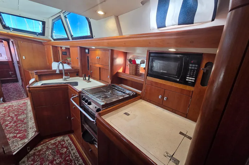 Slide: The Image of Interior of 1998 Oyster 485 Deck Saloon yacht, featuring a wooden galley and cozy cabin. - 13