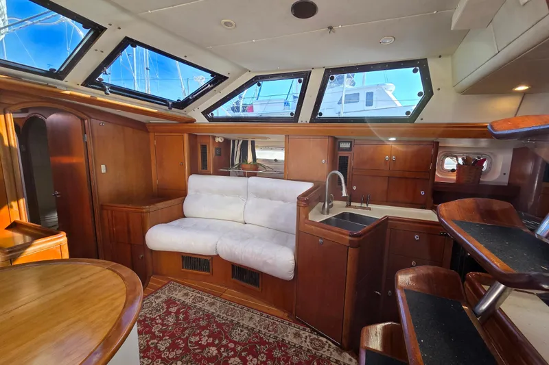 Slide: The Image of Luxurious interior of 1998 Oyster 485 Deck Saloon yacht with white seating and wooden finishes. - 9