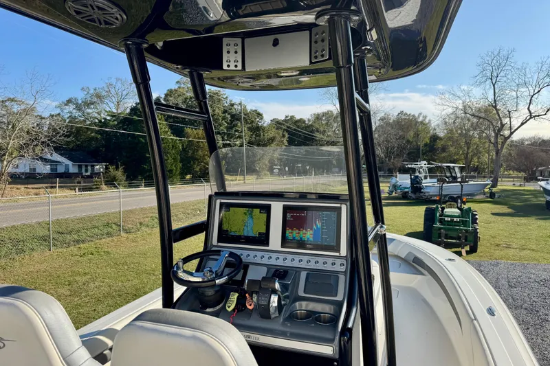 Slide: The Image of 2021 ShearWater 27 Carolina boat dashboard with navigation screens and steering wheel. - 14