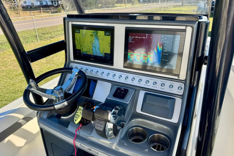 Slide: The Image of 2021 ShearWater 27 Carolina boat dashboard with dual Garmin displays and steering wheel. - 5