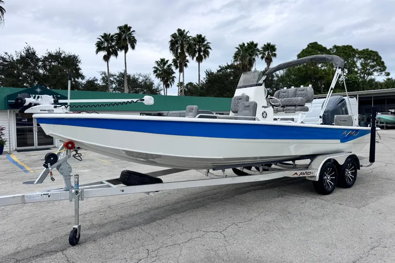 The Image of 2026 Avid 23 Fusion boat on trailer, blue and white design, parked outdoors. - 1