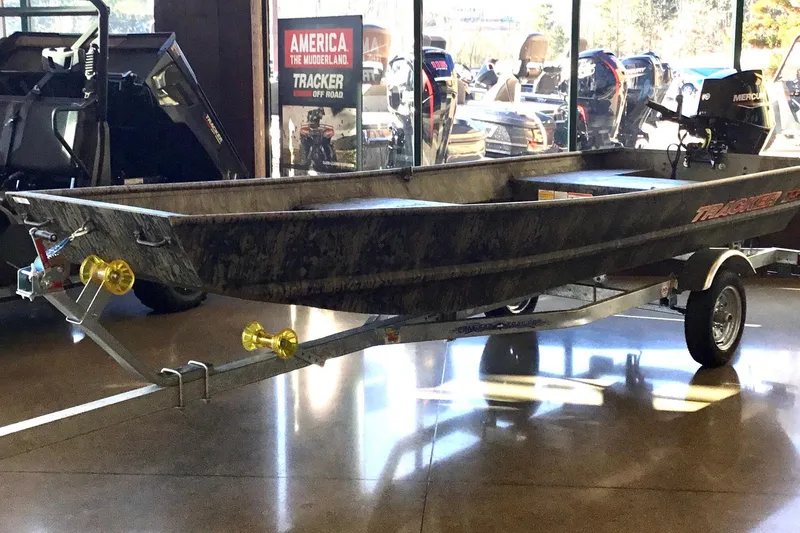 The Image of 2026 Tracker Grizzly 15 Jon boat on display in showroom with trailer. - 0