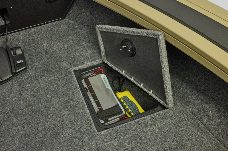 Slide: The Image of 2026 Tracker Targa V-19 Combo boat storage compartment with equipment and carpeted interior. - 13