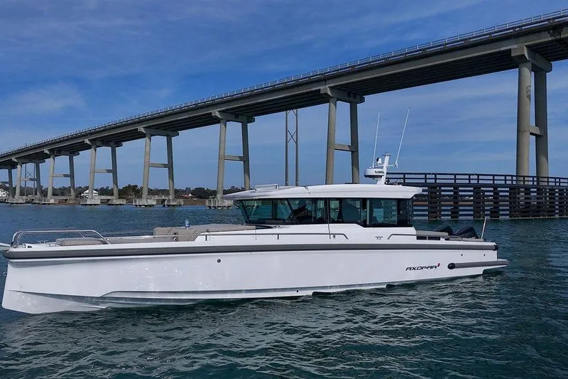 The Image of 2023 Axopar 37 XC Cross Cabin boat cruising under a large bridge. - 0