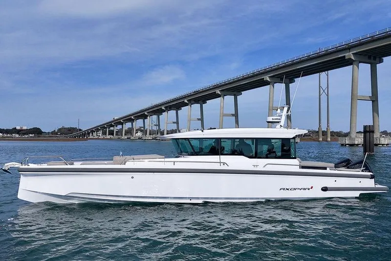 Slide: The Image of 2023 Axopar 37 XC Cross Cabin boat cruising under a large bridge. - 1