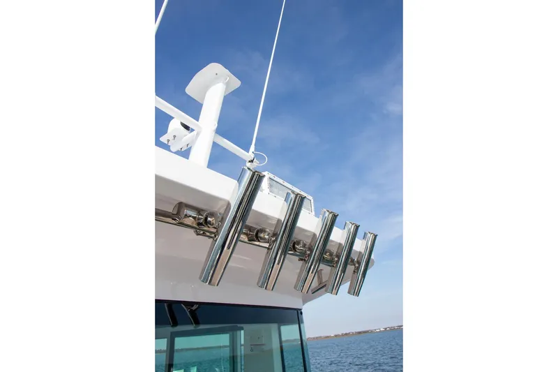 Slide: The Image of 2023 Axopar 37 XC Cross Cabin boat with rod holders against blue sky. - 17