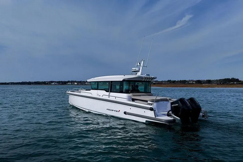 Slide: The Image of 2023 Axopar 37 XC Cross Cabin boat on calm water under clear sky. - 2