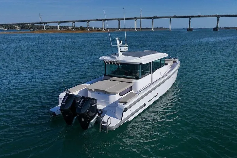 Slide: The Image of 2023 Axopar 37 XC Cross Cabin boat cruising on blue water near a bridge. - 4
