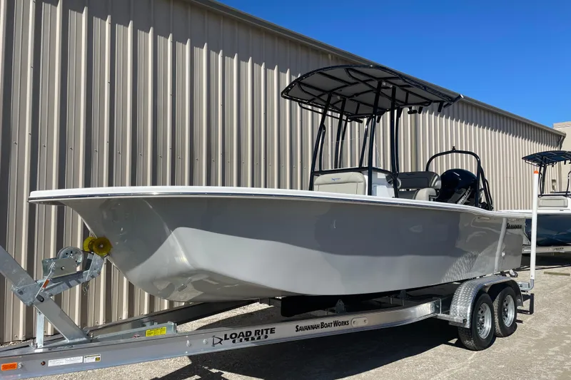 Slide: The Image of 2023 Savannah SS21 boat on trailer, parked outside a metal building. - 14