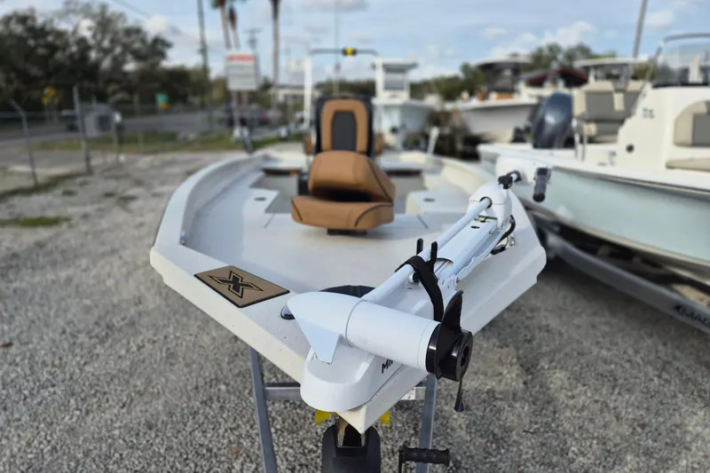 Slide: The Image of 2026 Xpress H22B Bay boat with trolling motor, parked on gravel lot. - 6