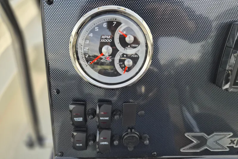 Slide: The Image of 2026 Xpress H22B Bay boat dashboard with RPM gauge and control switches. - 9
