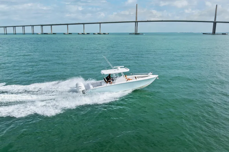 Slide: The Image of 2022 Jupiter 34 HFS boat cruising on open water near a long bridge. - 6
