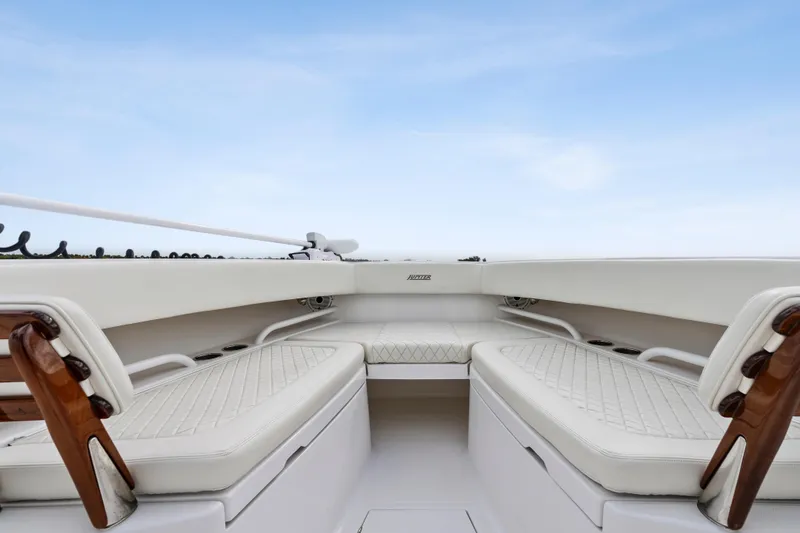 Slide: The Image of 2022 Jupiter 34 HFS boat interior with white cushioned seating and wooden accents. - 9