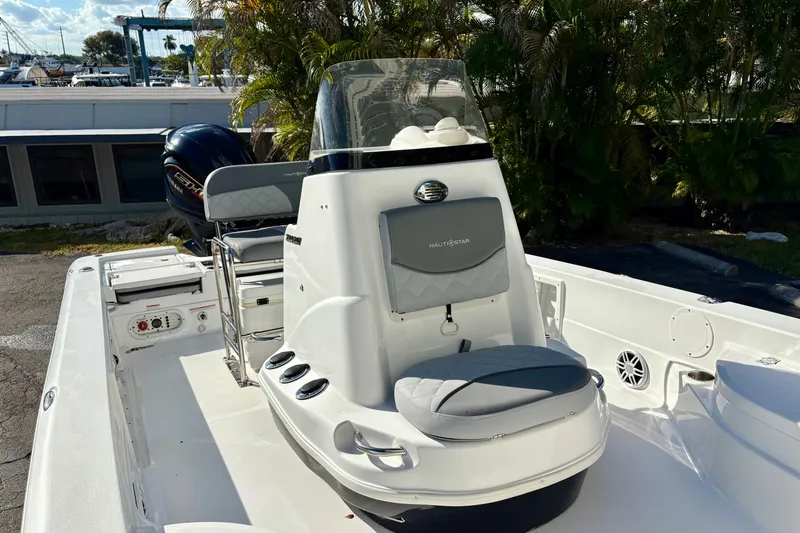 Slide: The Image of 2025 NauticStar 224 Bay boat interior with seating and console, parked outdoors. - 7