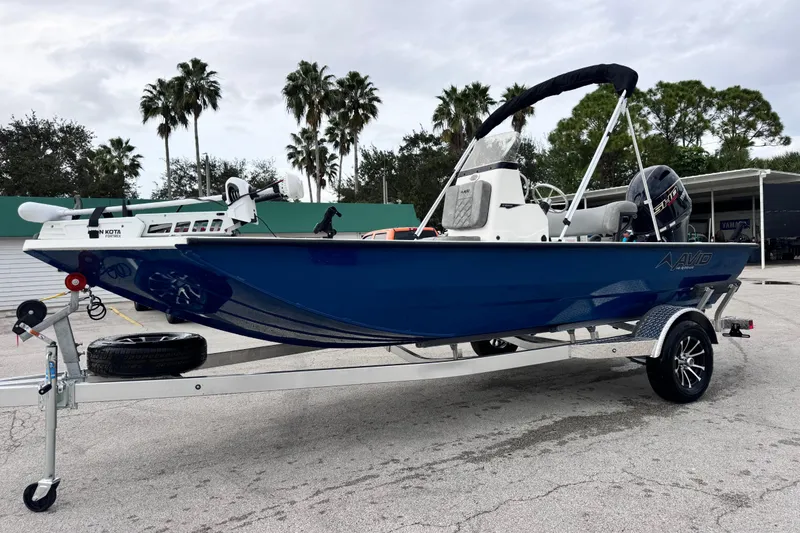 Slide: The Image of 2026 Avid 18 Rogue CC boat on trailer, blue hull, palm trees in background. - 2