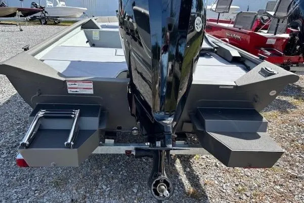 Slide: The Image of 2026 SeaArk Shadow 17 boat rear view with motor and ladder on gravel surface. - 4