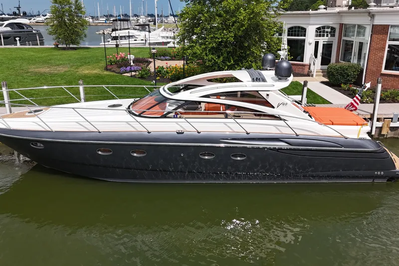 The Image of 2006 Princess V48 yacht docked at a marina, surrounded by lush greenery and waterfront views. - 0