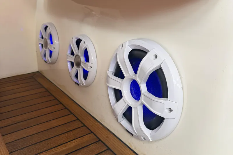 Slide: The Image of White speakers with blue lights on a 2006 Princess V48 yacht's wooden deck. - 13