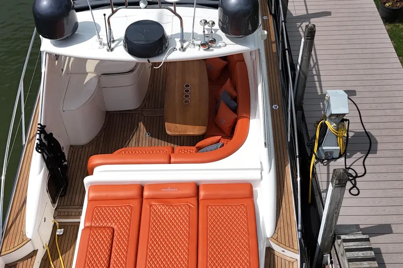 Slide: The Image of 2006 Princess V48 yacht with orange seating, docked at a wooden pier. - 45