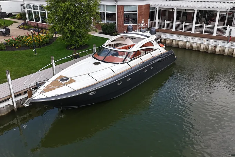 Slide: The Image of 2006 Princess V48 yacht docked by a waterfront building, surrounded by greenery. - 48
