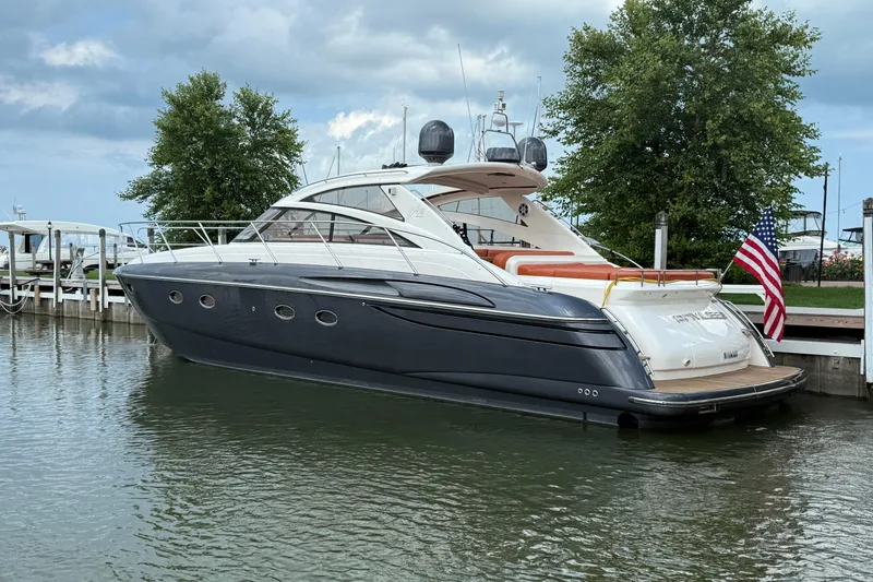 Slide: The Image of 2006 Princess V48 yacht docked, featuring sleek design and American flag. - 52