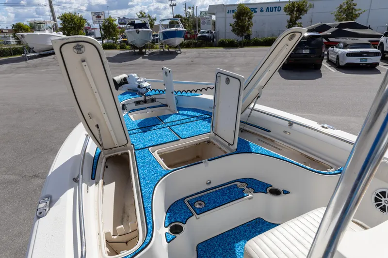 Slide: The Image of 2018 Sea Chaser 23 LX Bay Runner boat with open storage compartments in a parking lot. - 15