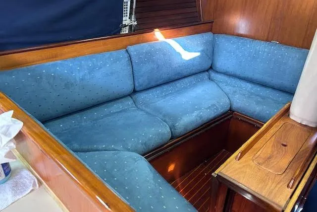 Slide: The Image of 1987 Beneteau First 375 sailboat interior with blue cushioned seating and wooden accents. - 11
