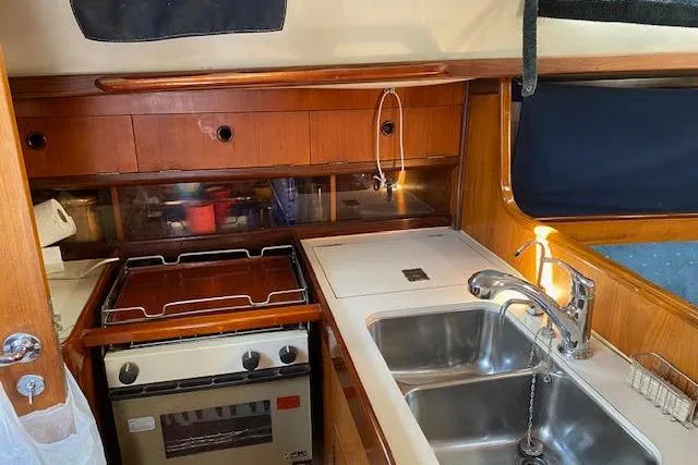Slide: The Image of 1987 Beneteau First 375 yacht kitchen with stove, sink, and wooden cabinetry. - 13