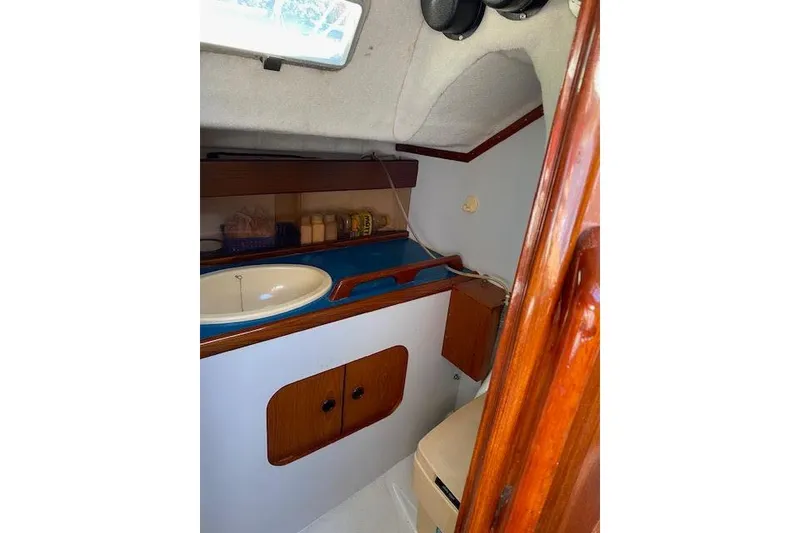 Slide: The Image of Interior of 1987 Beneteau First 375 sailboat, featuring a compact bathroom with sink and storage. - 17