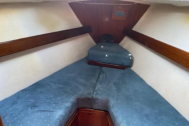 Slide: The Image of 1987 Beneteau First 375 cabin interior with blue cushions and wooden accents. - 22