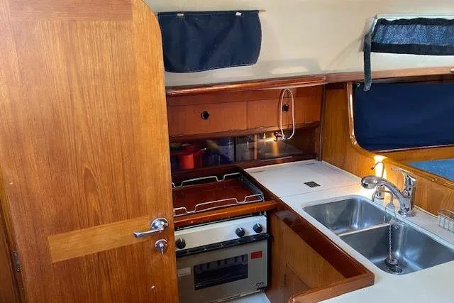 Slide: The Image of 1987 Beneteau First 375 yacht kitchen with stove, sink, and wooden cabinetry. - 25