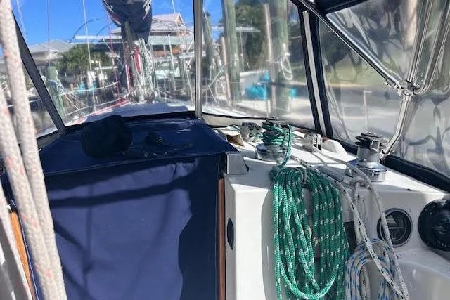 Slide: The Image of 1987 Beneteau First 375 sailboat cockpit with ropes and winches, under clear skies. - 8