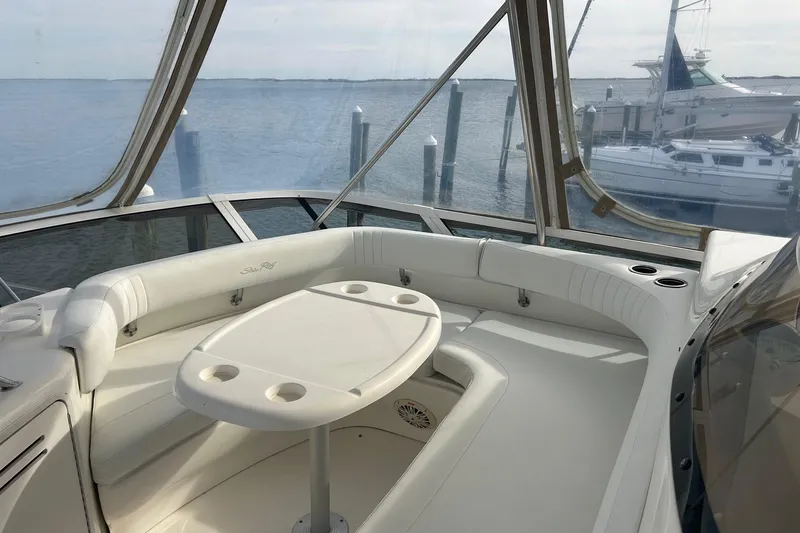 Slide: The Image of 2001 Sea Ray 480 Sedan Bridge yacht interior with seating and table, overlooking marina. - 14