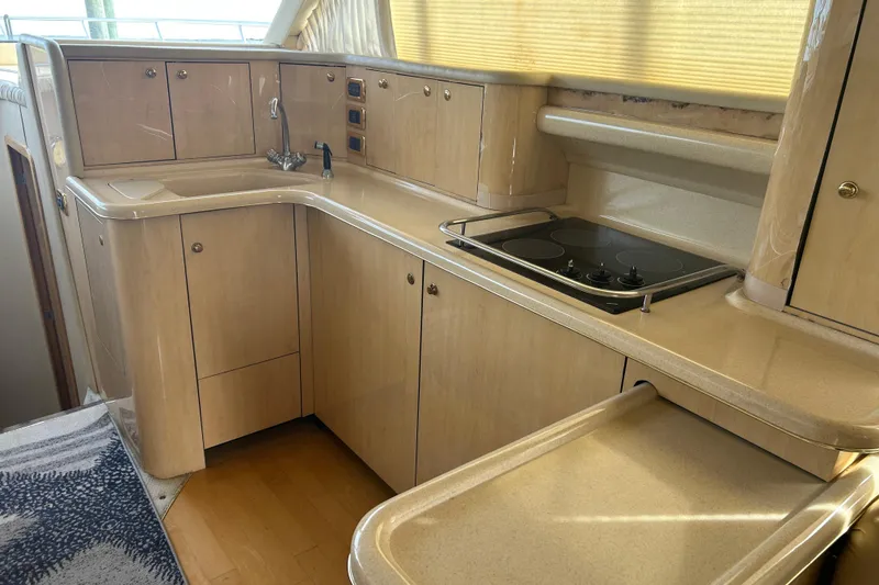 Slide: The Image of 2001 Sea Ray 480 Sedan Bridge yacht kitchen with light wood cabinetry and modern appliances. - 25