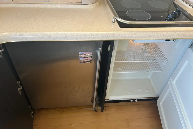 Slide: The Image of Kitchen area of a 2001 Sea Ray 480 Sedan Bridge with open fridge and stove. - 28