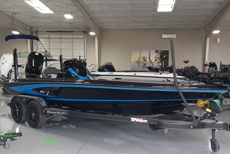 The Image of 2026 Triton 21XP Patriot boat in showroom, sleek black and blue design, on trailer. - 0