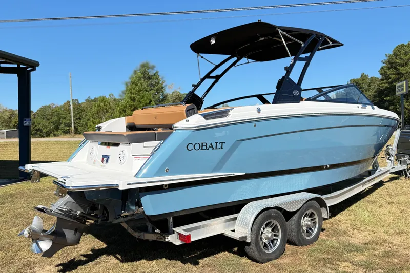 Slide: The Image of 2025 Cobalt R8 boat on trailer, blue and white design, parked on grass. - 7