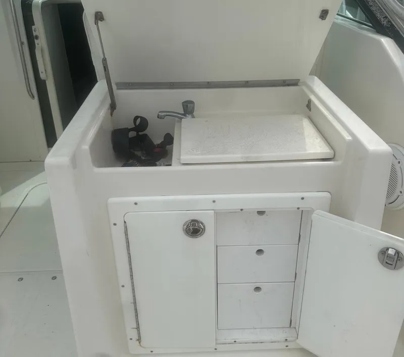 Slide: The Image of 1995 Tiara Sport 3100 boat sink and storage area with open cabinet and faucet. - 8