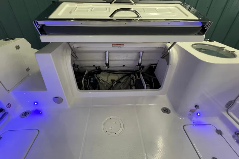 Slide: The Image of 2026 Robalo R257 Dual Console boat interior with open storage compartment and blue LED lights. - 19